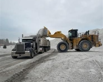 Construction dump truck unloading gravel with a hydraulic lift bed spilling material onto the ground, as a job site  
