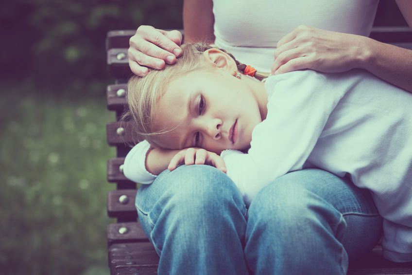 little girl being comforted in the lap of a woman