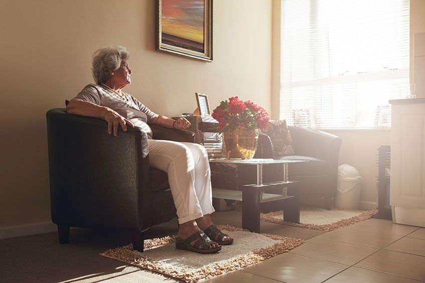 Elderly woman staring out the window emitting rays of sunlight