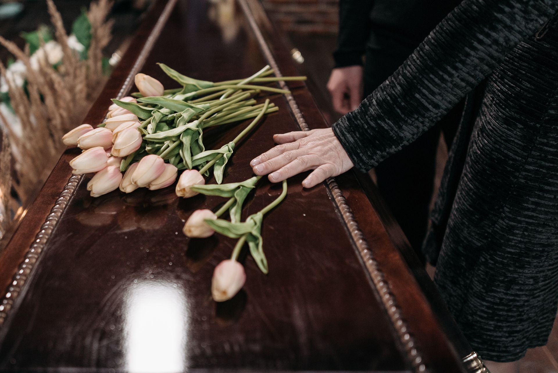 Hand on Casket With Flowers