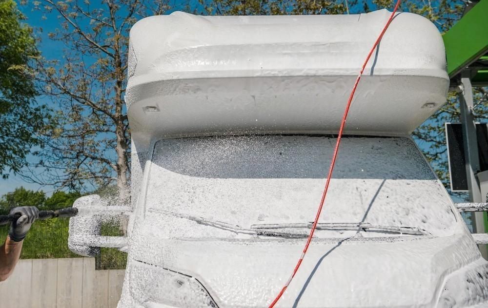 A person is washing a camper van with foam.