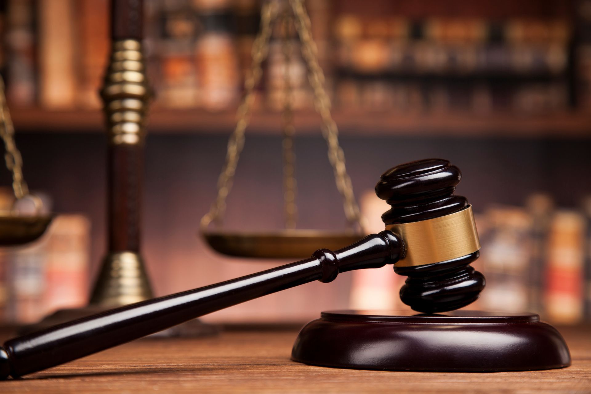 Gavel on a wooden block, scales of justice in the background, set on a desk in a law office.