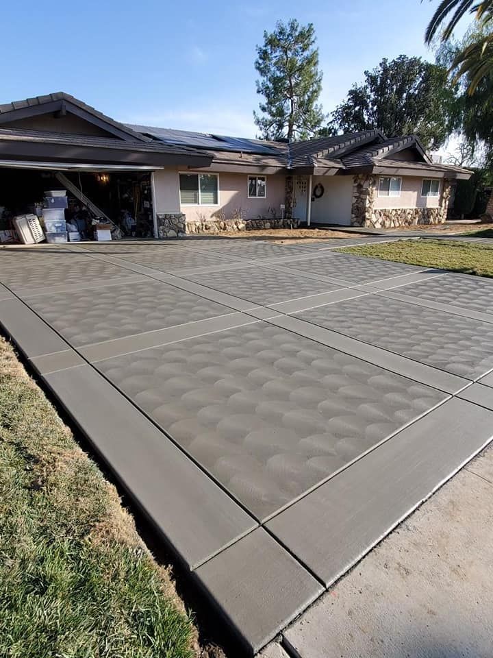 A concrete driveway leading to a house with a wooden fence.