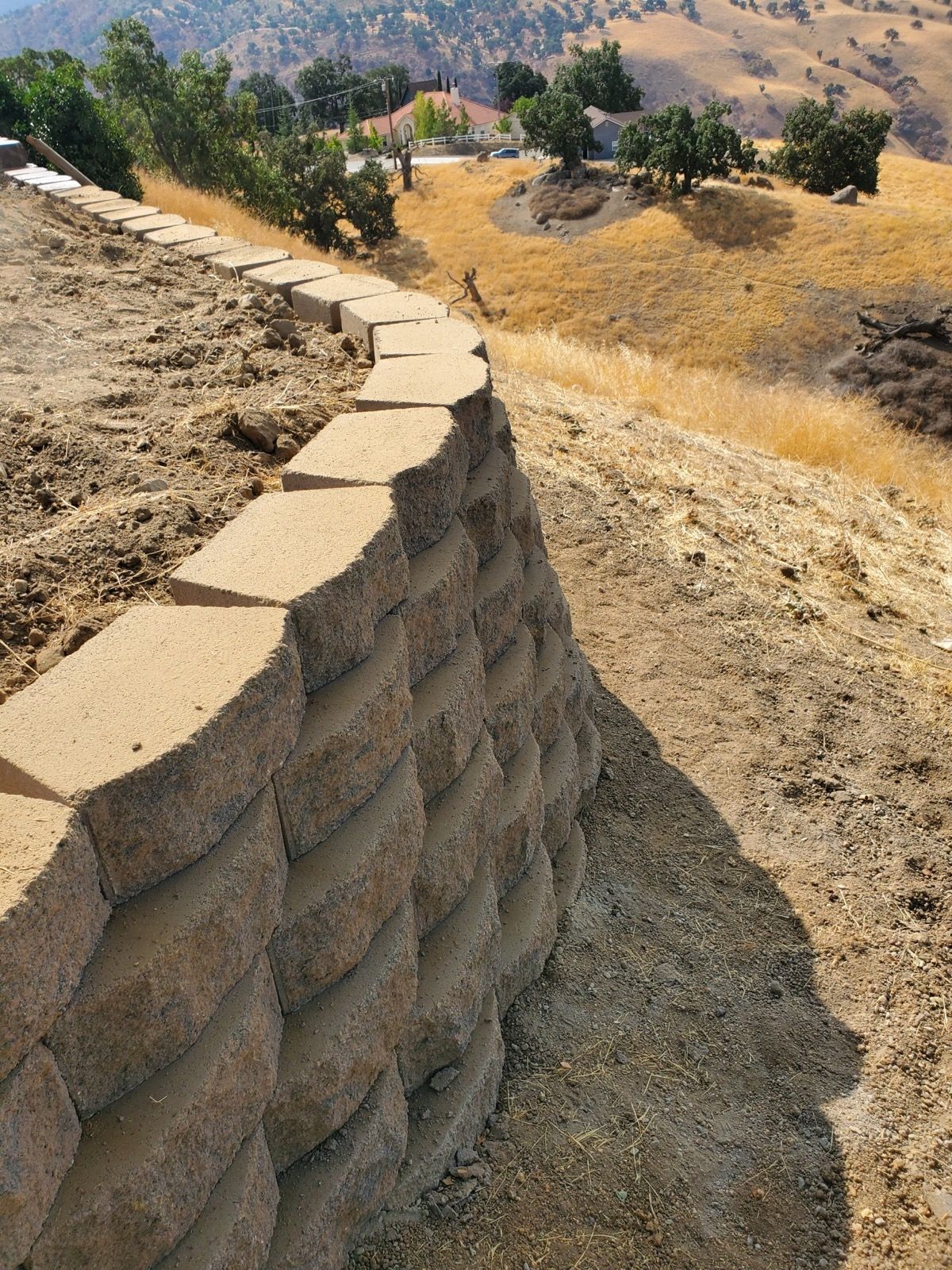 A stone wall is sitting on top of a dirt hill.