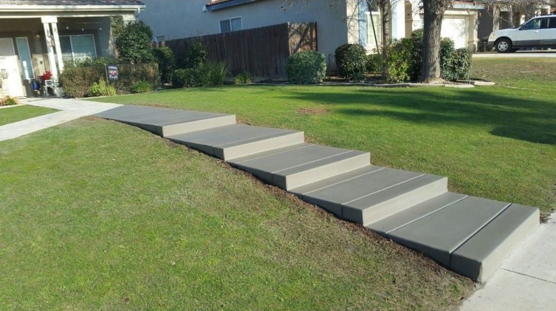A concrete walkway with steps leading up to a house.