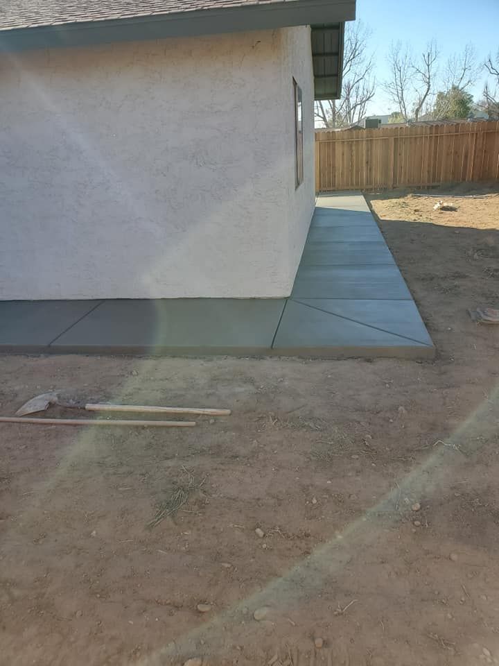 A concrete walkway is being built in the backyard of a house.