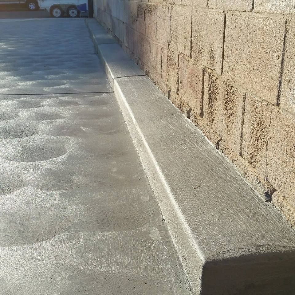 A concrete sidewalk with a brick wall in the background