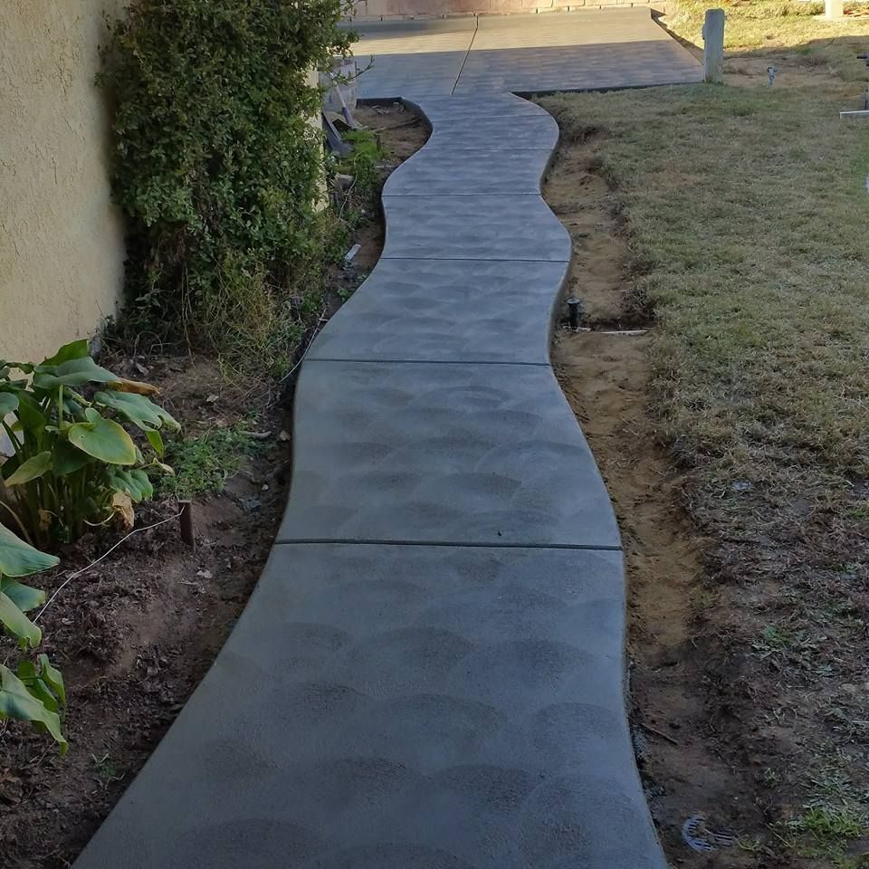 A concrete walkway is going through a lush green yard.