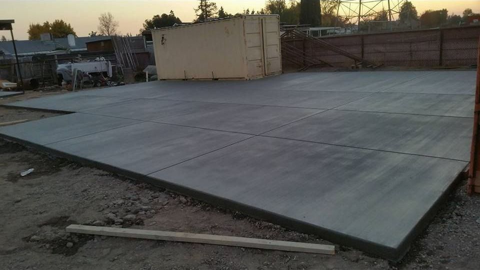 A large concrete floor is being built in a parking lot.