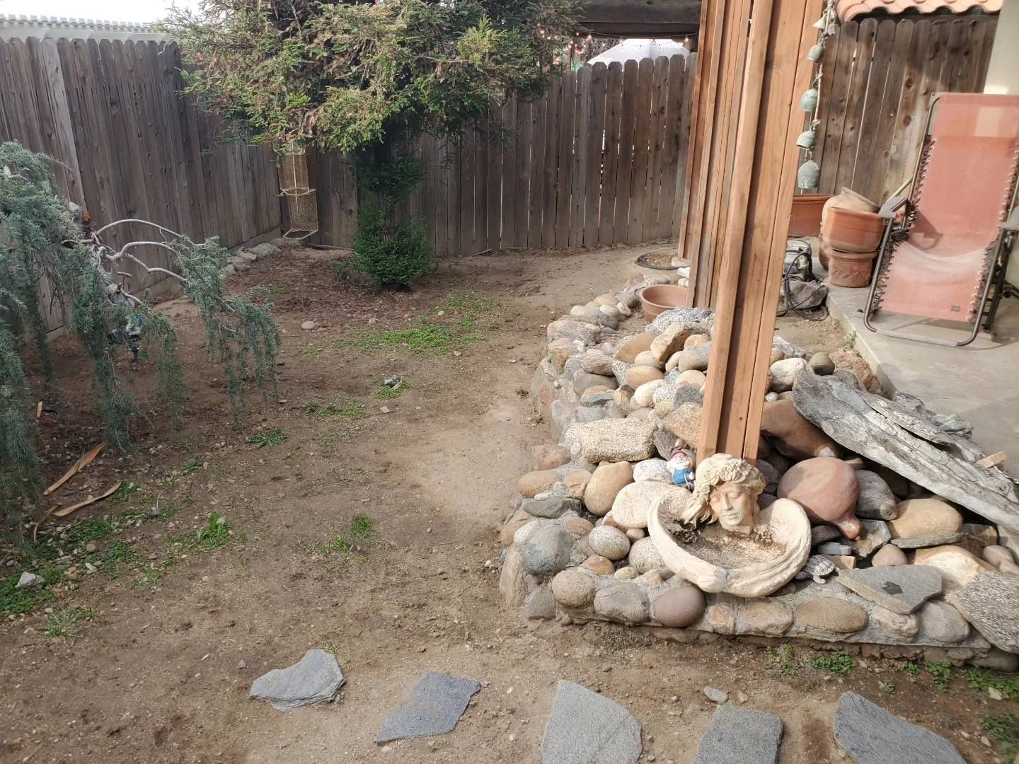 A backyard with rocks and a wooden fence