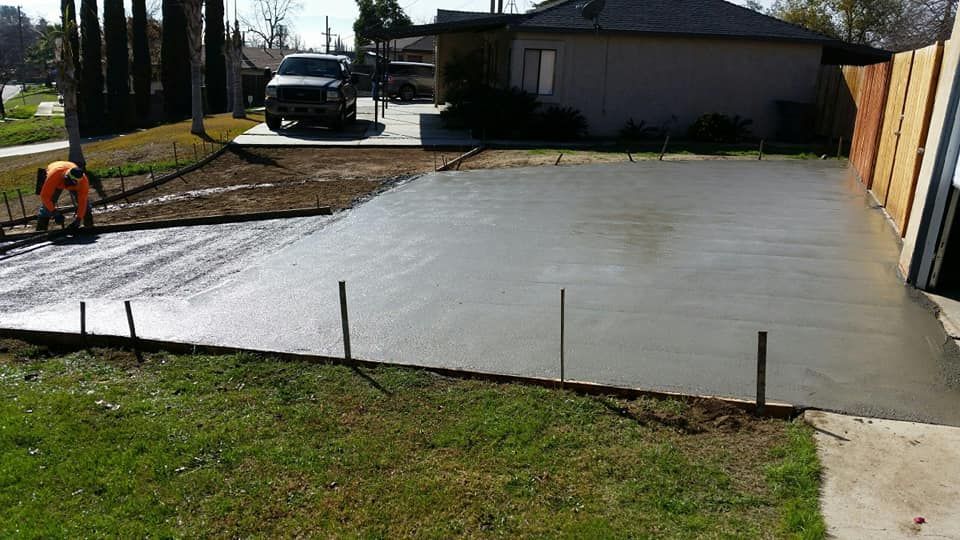 A man is working on a concrete driveway in front of a house.