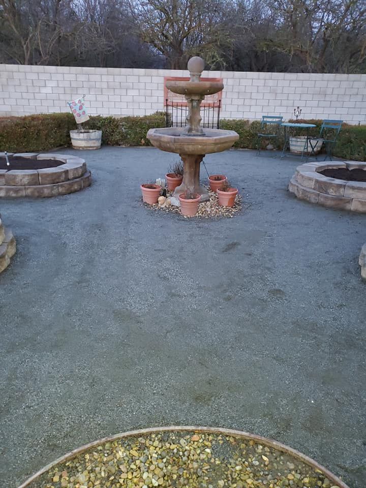 A fountain in a garden with potted plants around it
