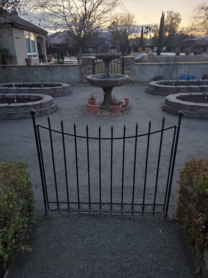 A wrought iron fence surrounds a fountain in a garden