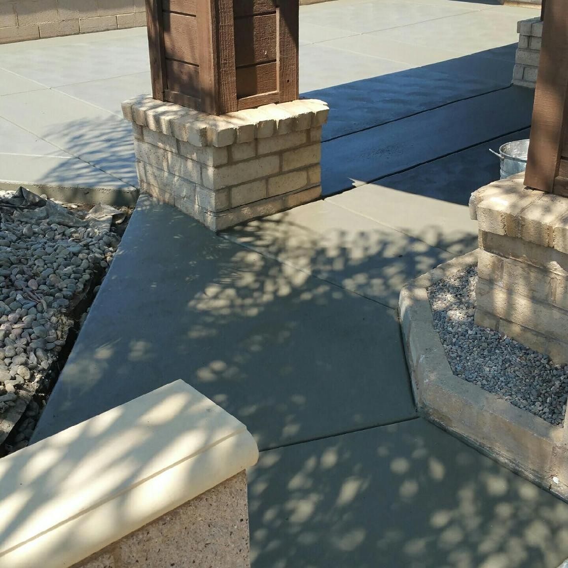 A concrete walkway with brick pillars and gravel