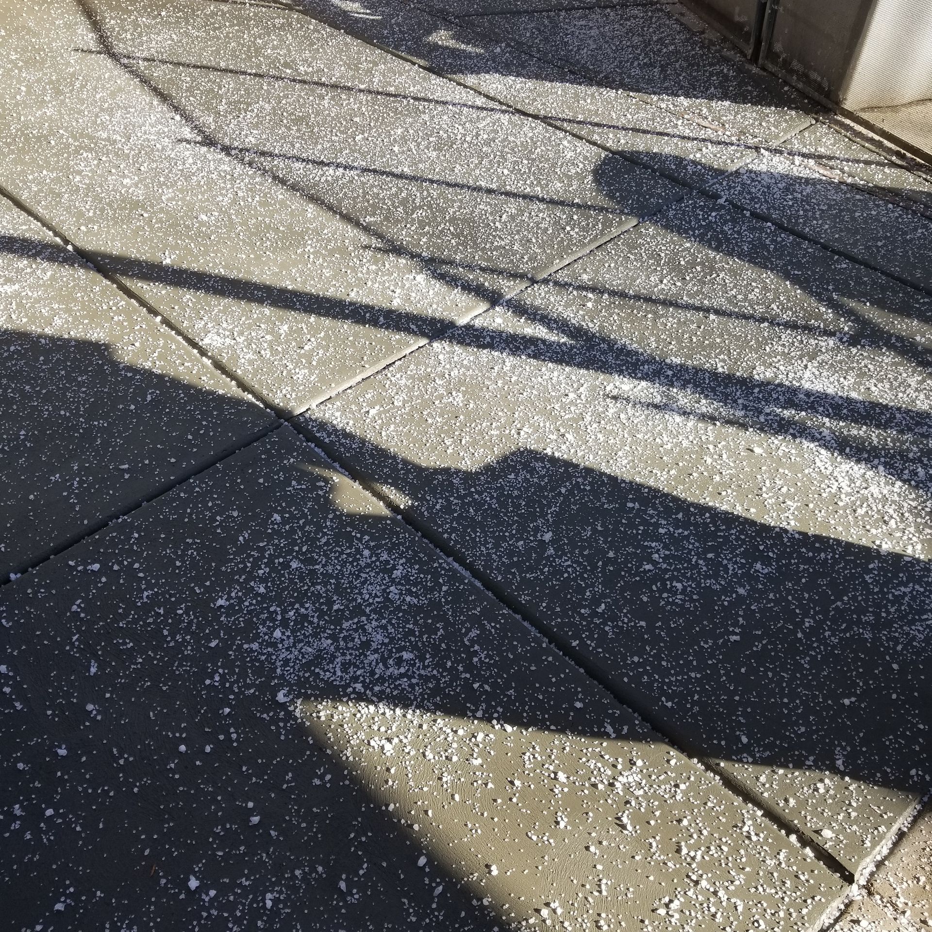 A shadow of a person is cast on a sidewalk.