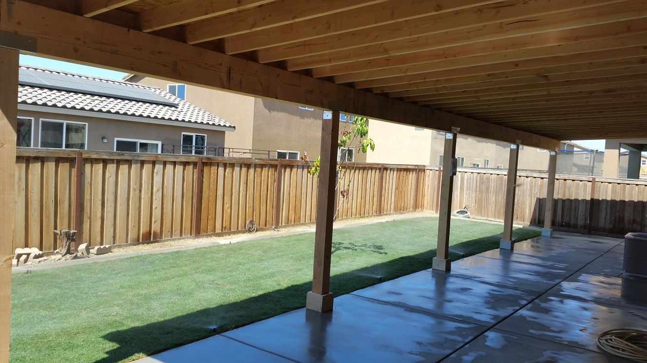 A covered patio with a wooden fence in the background.