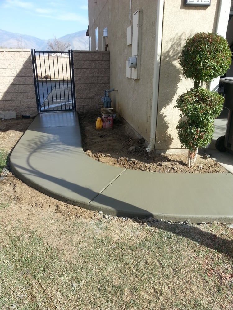 A concrete walkway is being built in front of a house.
