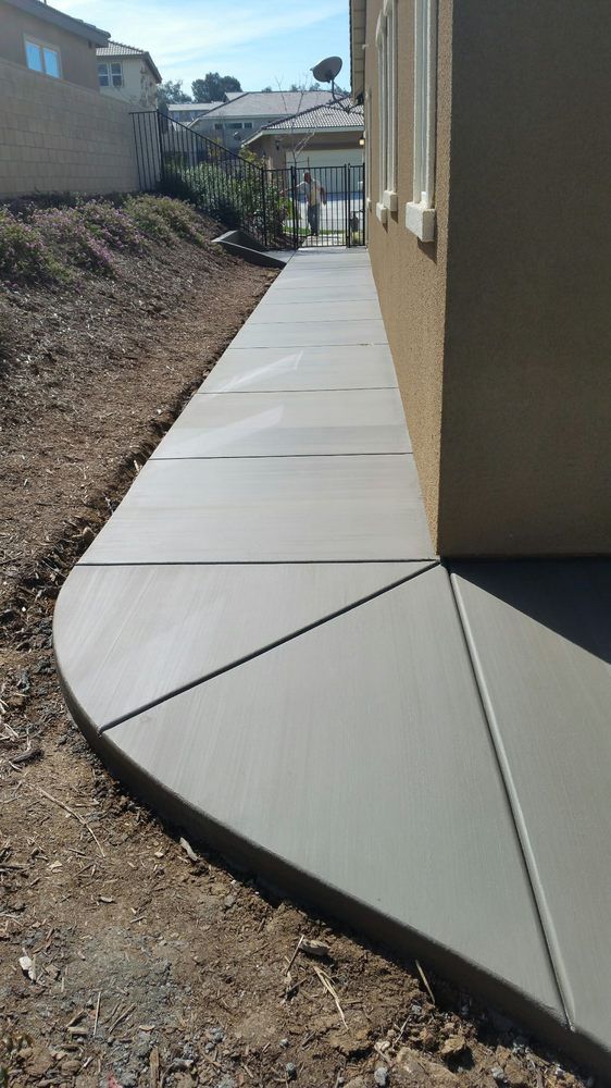 A concrete sidewalk is being built in front of a house.