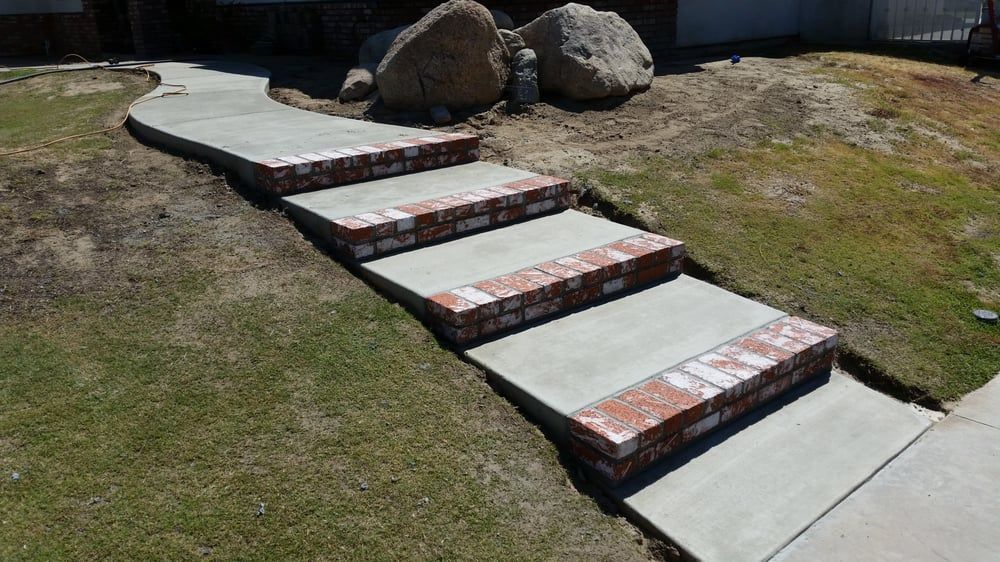 A concrete walkway with brick steps leading up to a house.