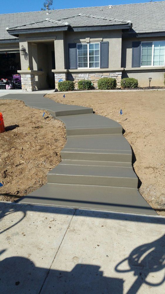 A concrete walkway is being built in front of a house.