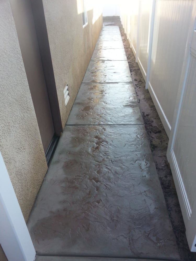 A concrete walkway with a white fence in the background