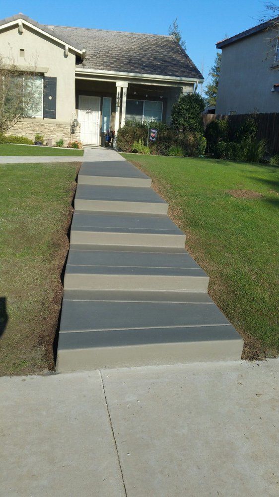 A concrete walkway with steps leading up to a house.