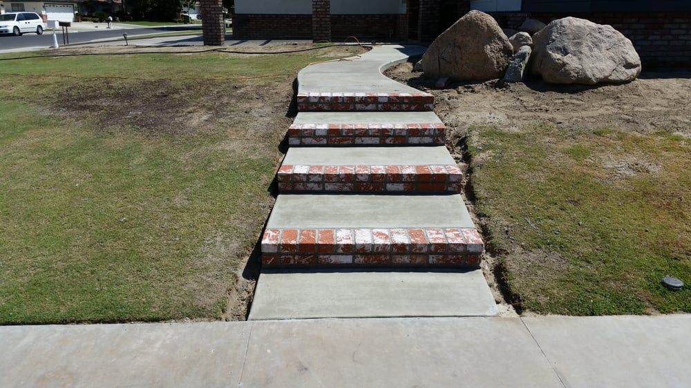 A concrete walkway with brick steps leading up to a house