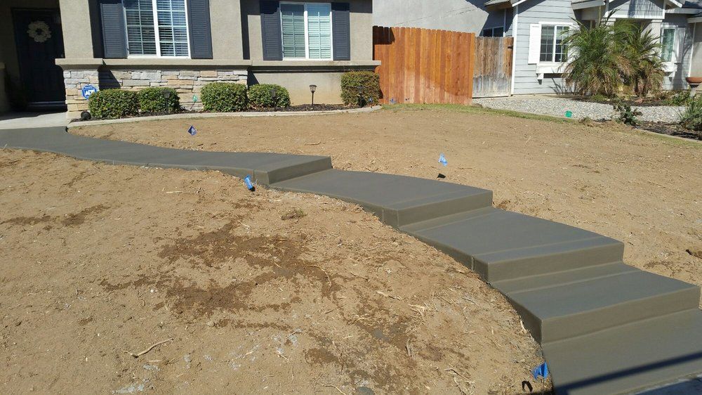 A concrete walkway is being built in front of a house.