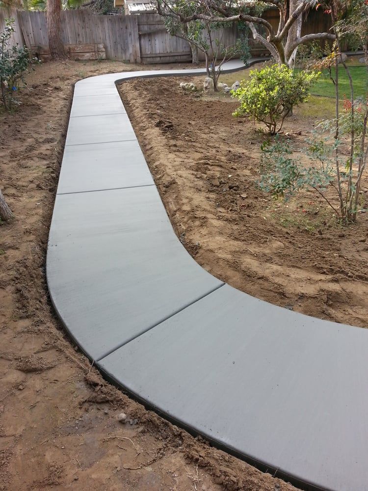 A concrete walkway is being built in a backyard.
