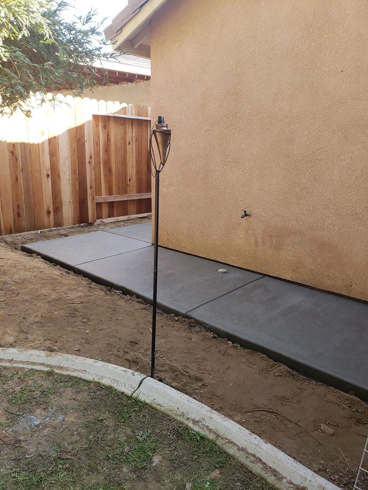 A concrete walkway is being built in the backyard of a house.