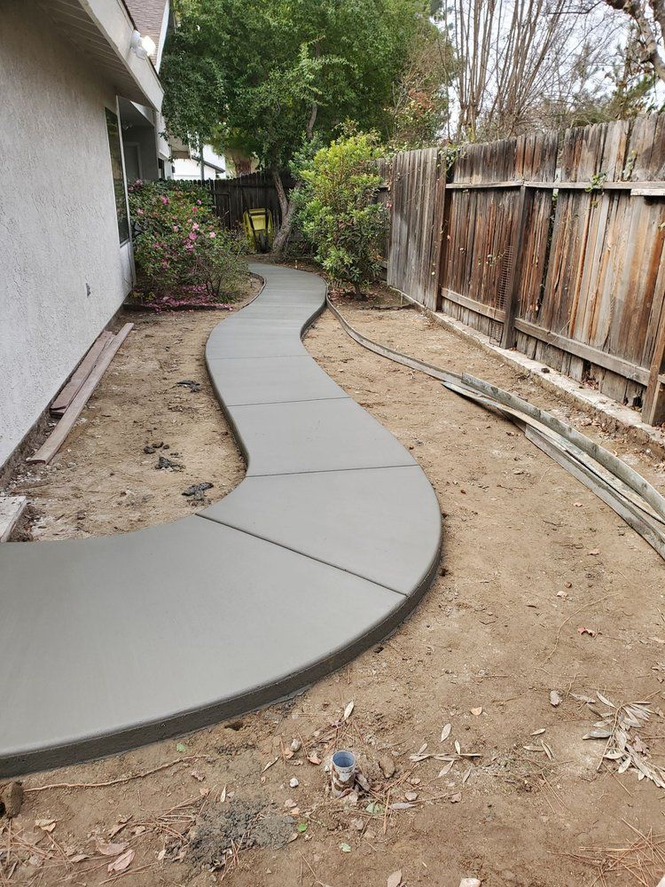 A concrete walkway is being built in the backyard of a house.