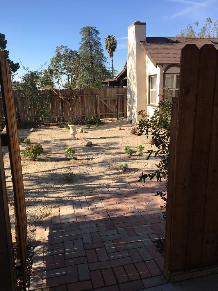 A wooden fence leading to a house with a palm tree in the background