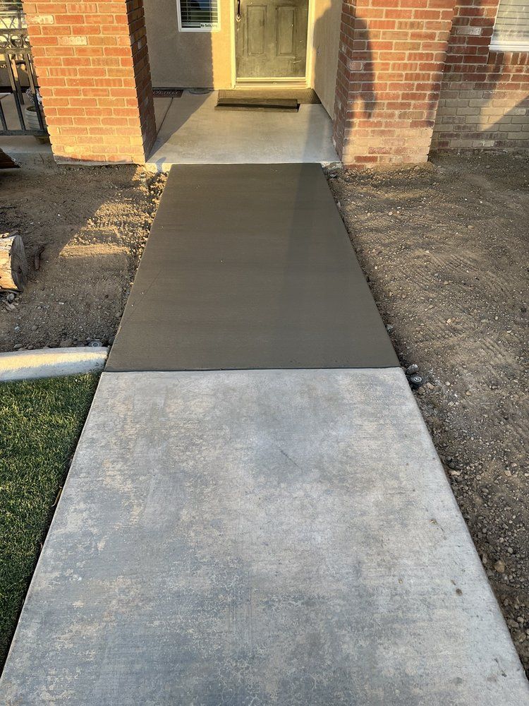 A concrete walkway is being built in front of a brick house.