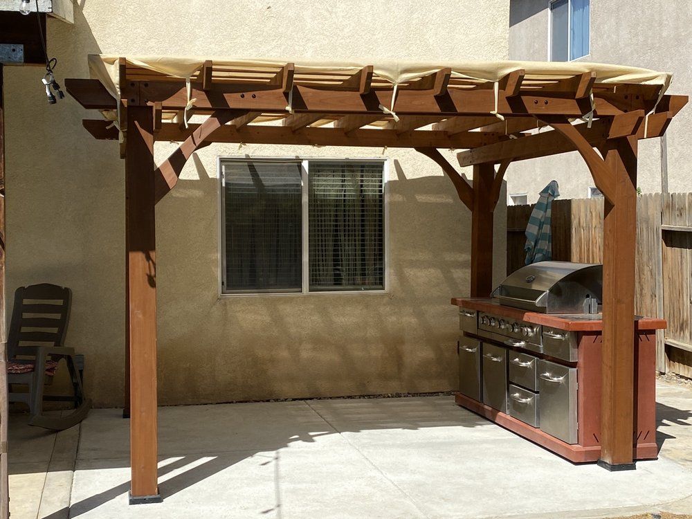 A wooden pergola with a grill underneath it