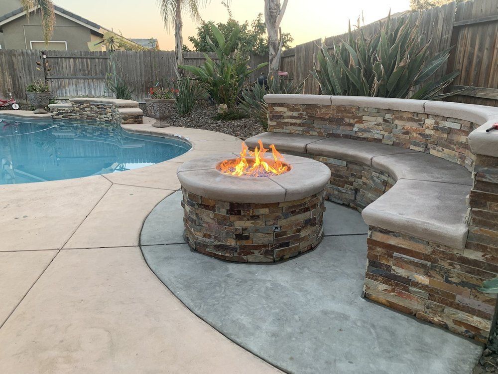 A fire pit is sitting next to a swimming pool.