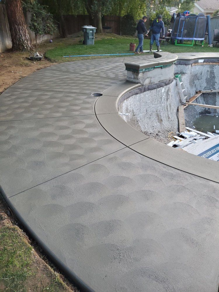 A concrete walkway is being built around a swimming pool.