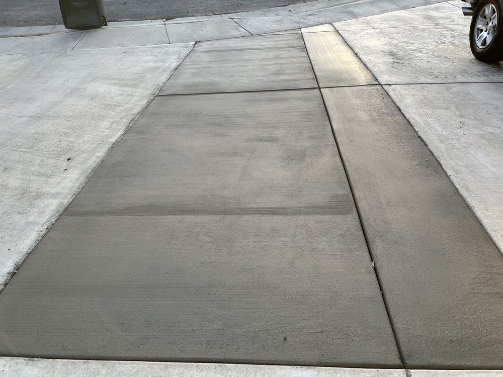 A concrete sidewalk with a car parked on the side of it.