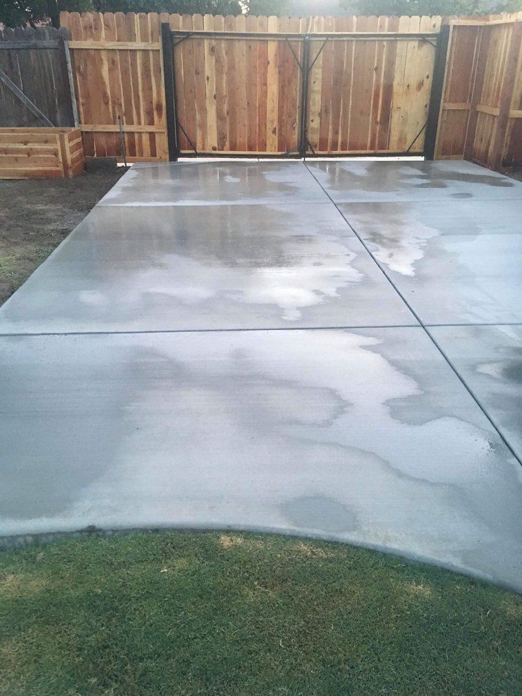 A concrete driveway with a wooden fence in the background.
