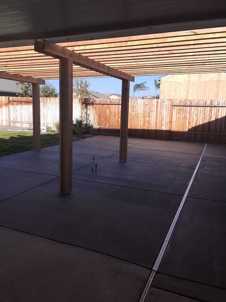 A patio with a pergola and a wooden fence in the background