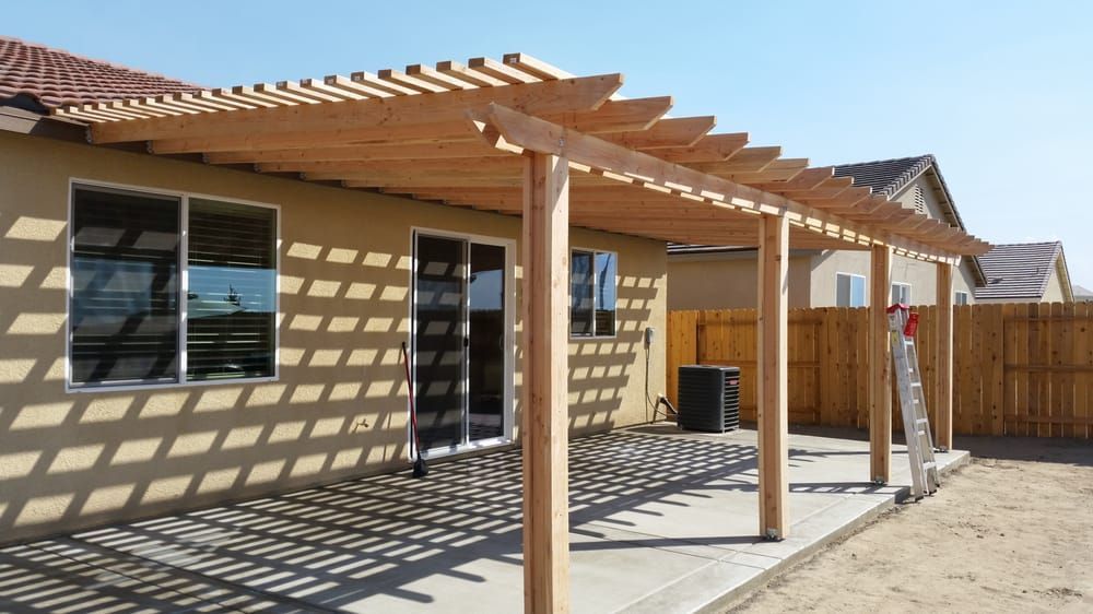 A pergola is being built in the backyard of a house