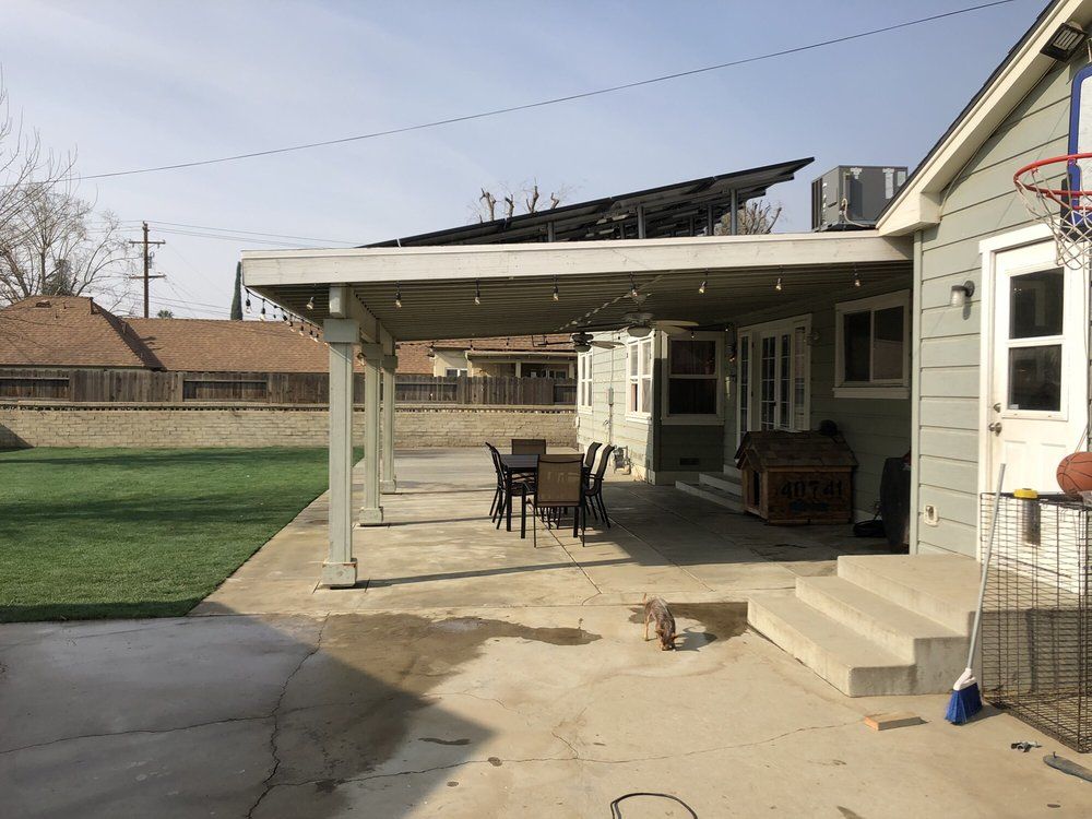 The backyard of a house with a covered patio and a basketball hoop.