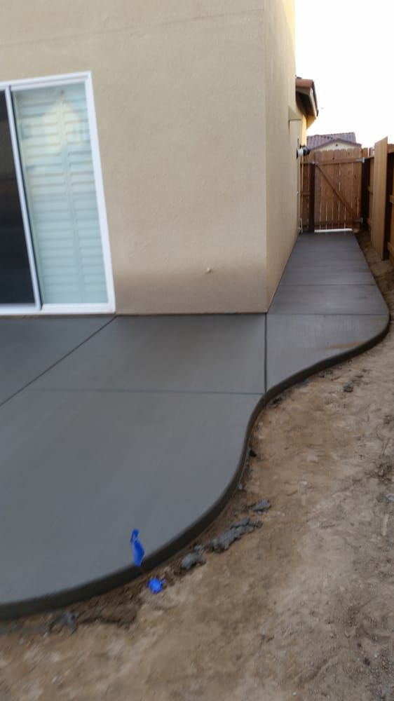 A concrete walkway leading to a house with a sliding glass door.