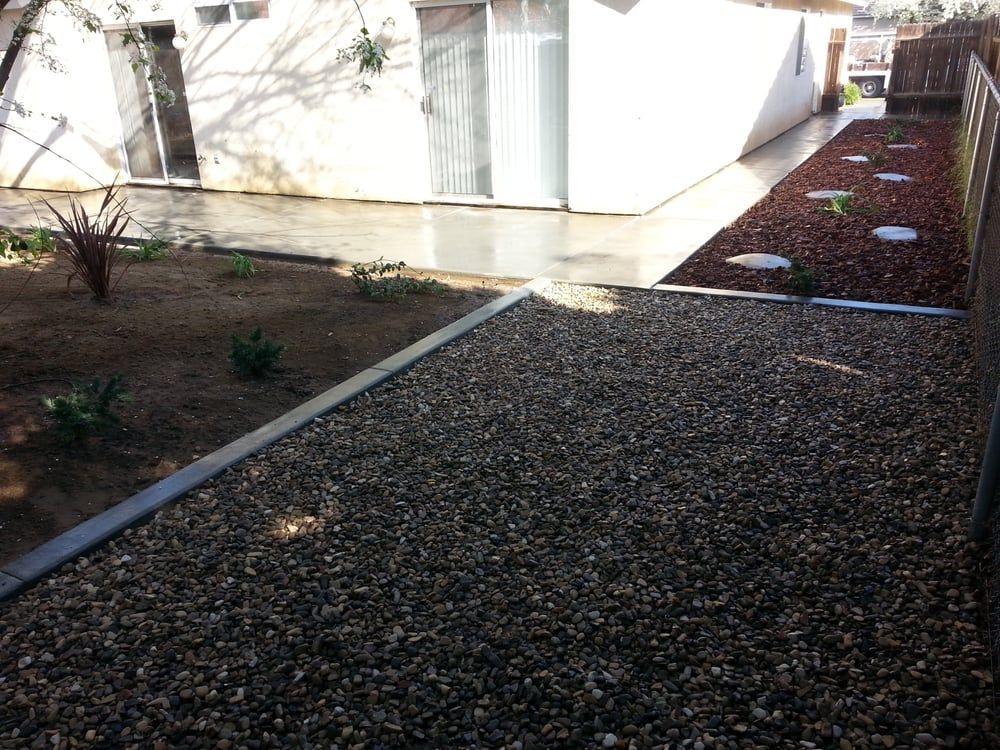 A gravel driveway leading to a white house