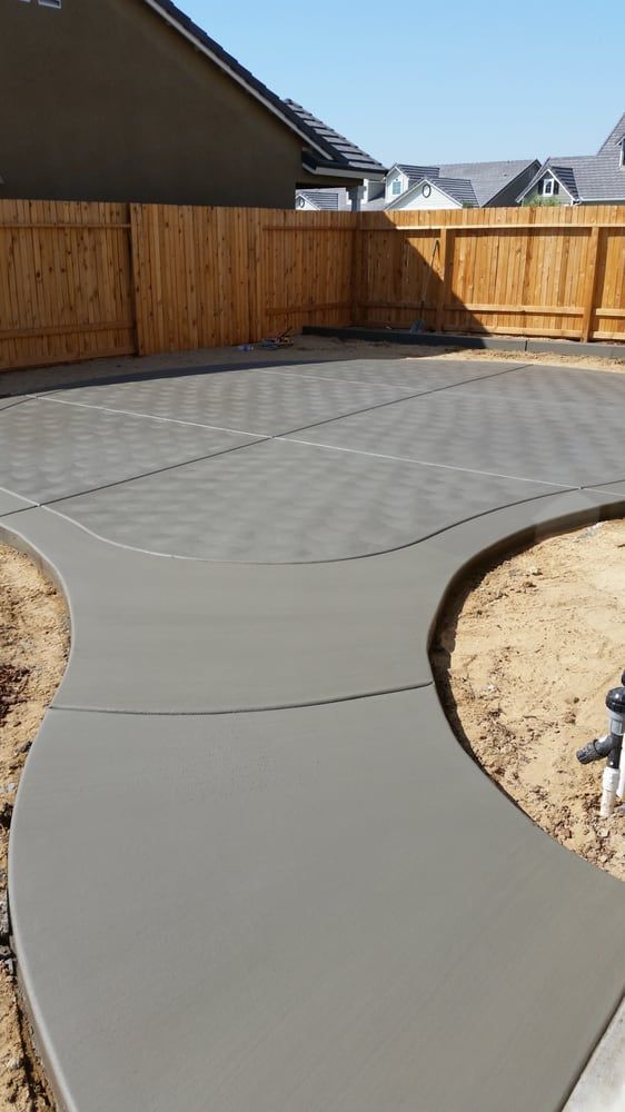 A concrete walkway with a wooden fence in the background.