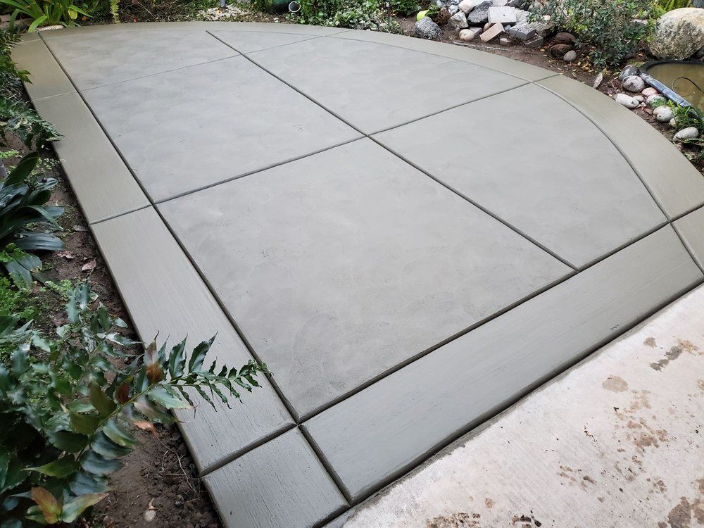A concrete walkway with a few plants in the background