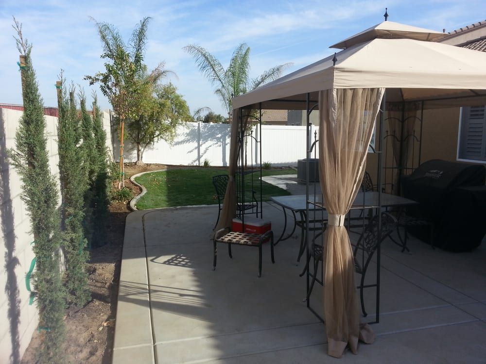 A gazebo with a table and chairs in a backyard