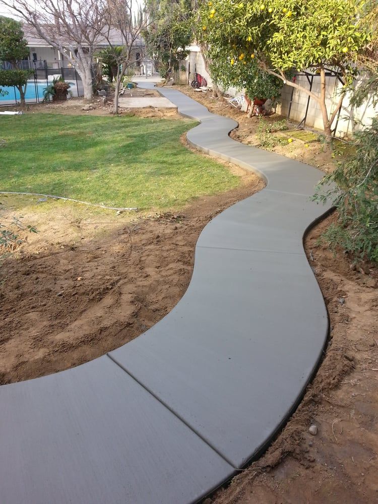A concrete walkway is going through a grassy area.