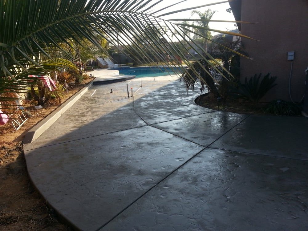 A concrete walkway leading to a pool with palm trees in the background