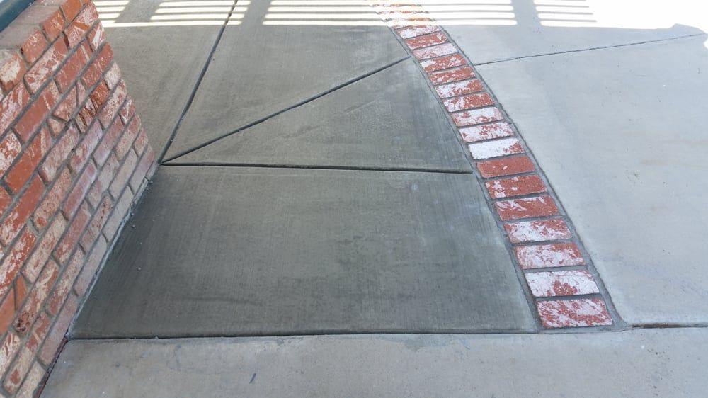 A sidewalk with a brick wall in the background