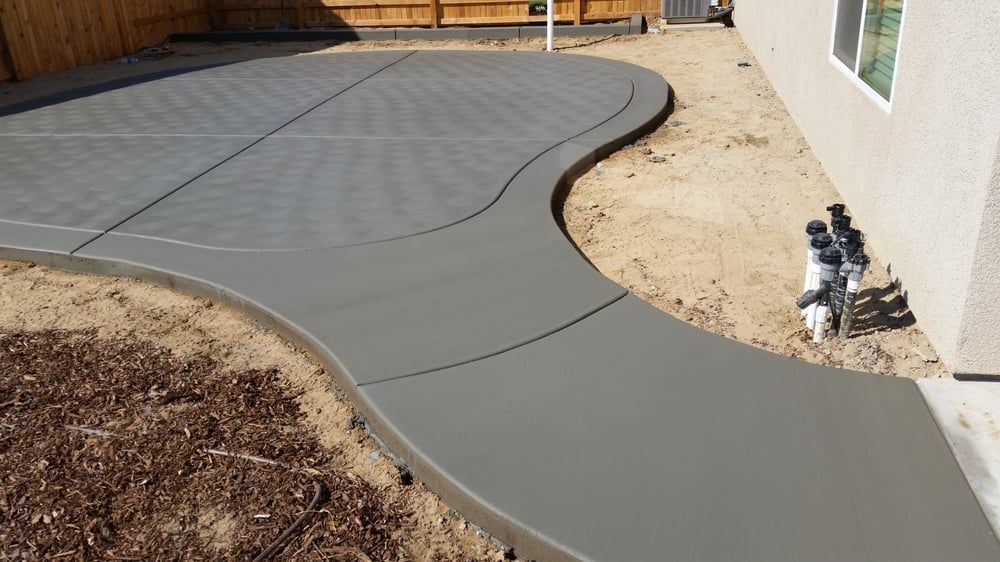A concrete walkway is being built in the backyard of a house.